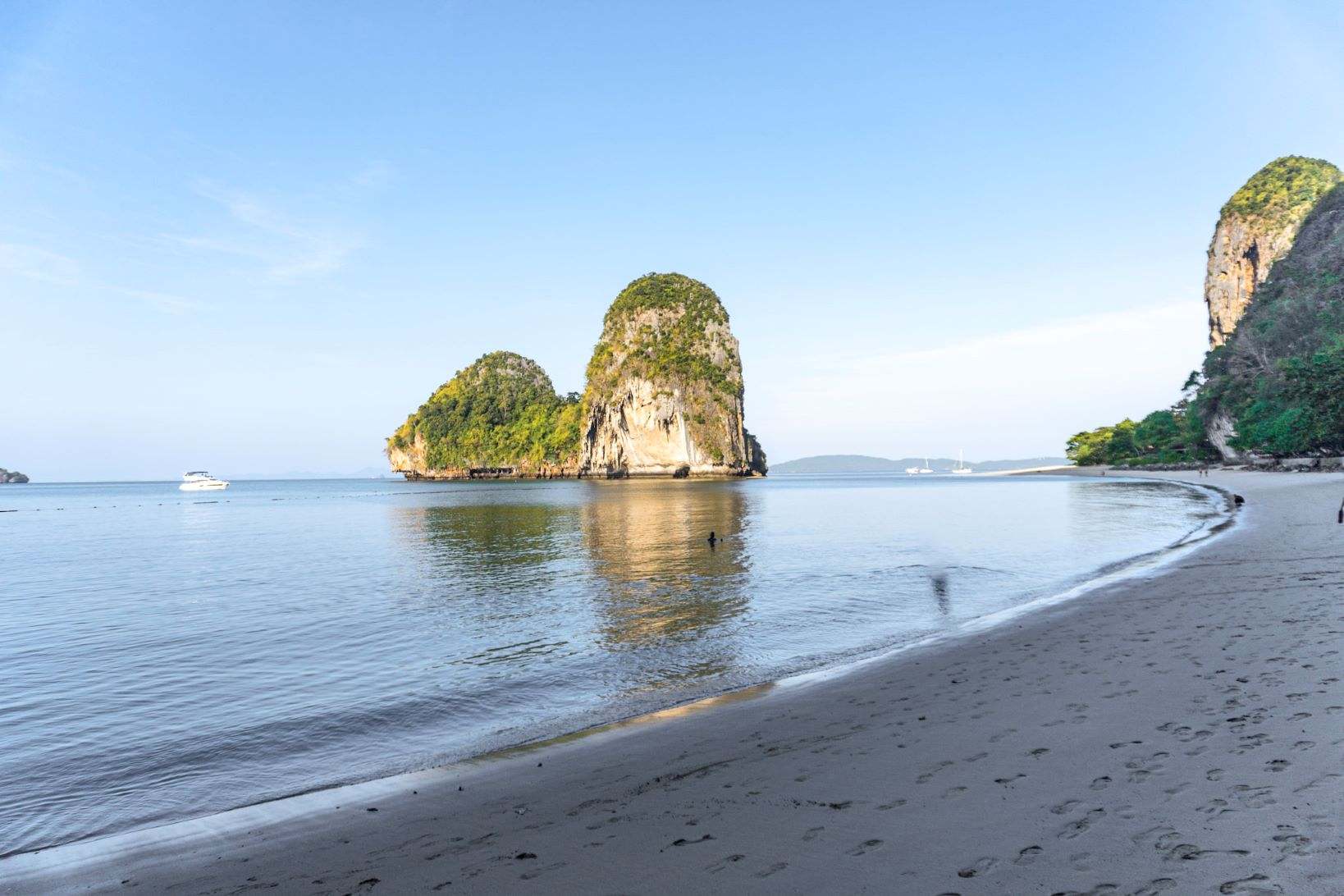brown sand near water with limestone cliff in the distance during sunrise