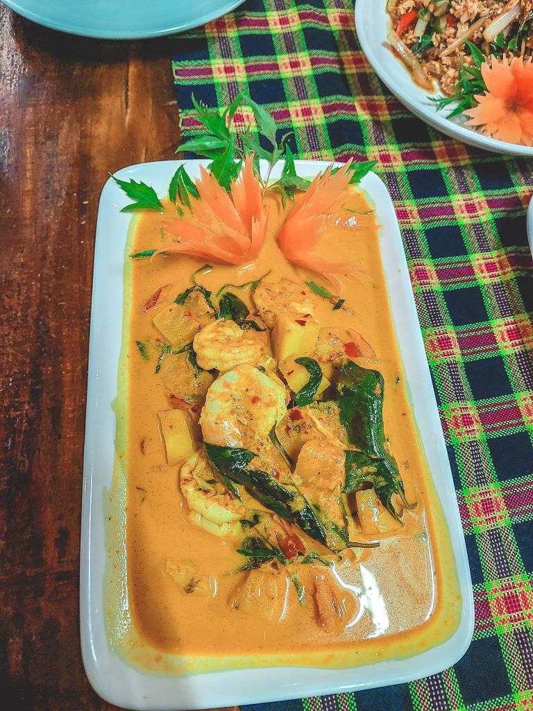 prawns cooked in a red curry with some orange carrots and green basil leaves