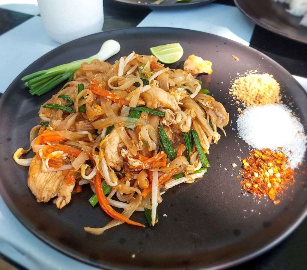 Noodles with julienne vegetables, green spring onions, side of crushed peanuts, chilli flakes