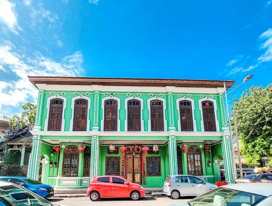 Green house with red car infront of it during daytime