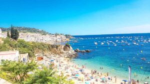 View from the cliff of the sea with people sitting on the sand sunbathing during daytime