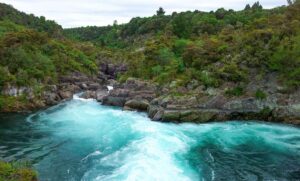 Beautiful blue water gushing down a river surrounded by trees during daytime