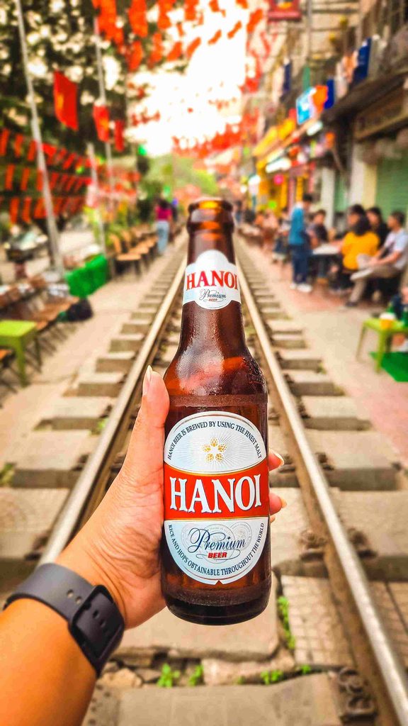 hand holding a bottle over train tracks during day time